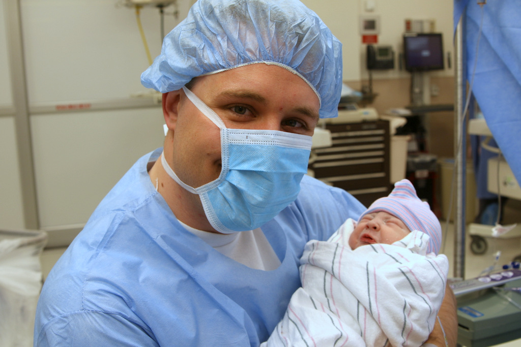 Russell holding Zadie while in scrubs